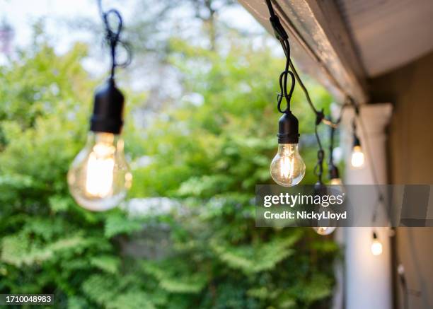 illuminated lights hanging on the porch of a home during the holidays - string light stock pictures, royalty-free photos & images