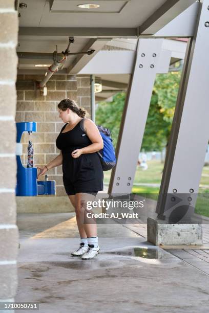 woman football player filling bottle with water from cooler - womens soccer stockfoto's en -beelden