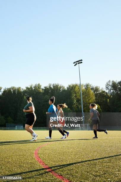 young women soccer team running together outdoors during a practice session - womens soccer stockfoto's en -beelden