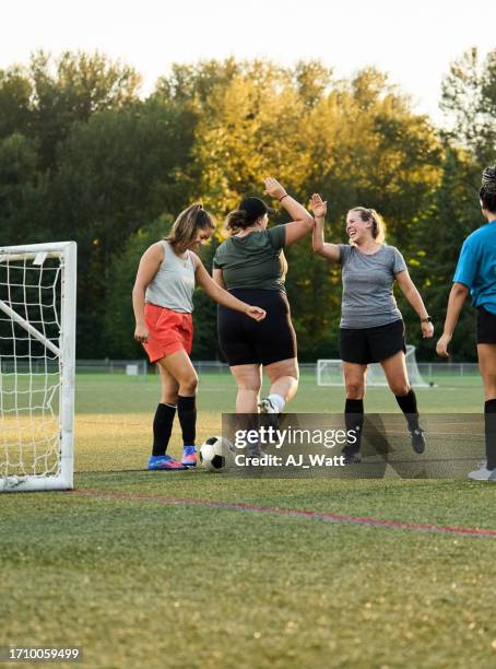 female players giving each other high fives while practising on soccer field - womens soccer stockfoto's en -beelden