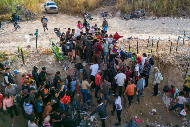 As seen from an aerial view, a U.S. Border Patrol agent supervises as immigrants walk into the United States after crossing the Rio Grande from...
