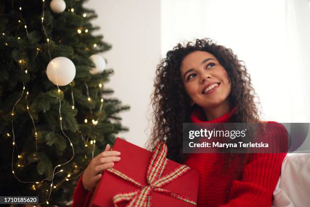 a black woman unpacks a gift. new year. christmas. holiday. christmas morning. surprise. - big beautiful black women 個照片及圖片檔