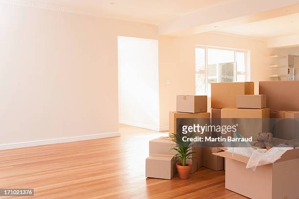 boxes stacked on wooden floor of new house - moving house stock pictures, royalty-free photos & images