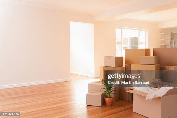 boxes stacked on wooden floor of new house - relocation stock pictures, royalty-free photos & images