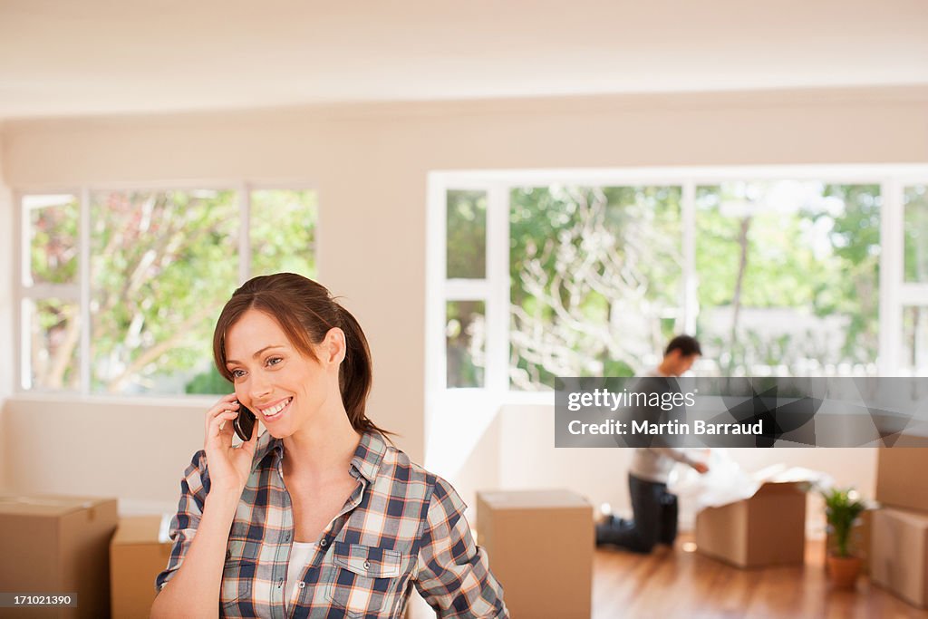 Mujer hablando por teléfono celular en casa nueva