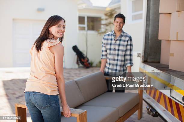 couple carrying sofa from moving van into new house - carrying sofa stock pictures, royalty-free photos & images