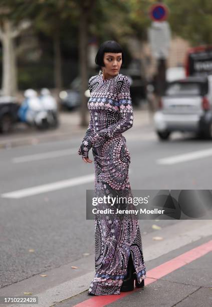 Kiwi Lee is seen outside Leonard Paris show wearing silver earrings, black and pink patterned narrow dress, black plateau boots during the Womenswear...