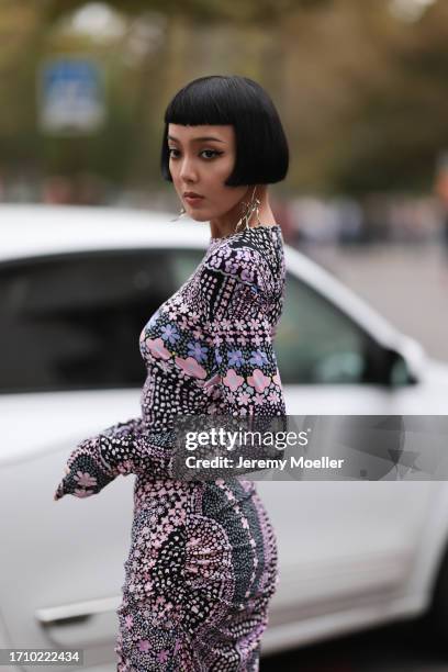 Kiwi Lee is seen outside Leonard Paris show wearing silver earrings, black and pink patterned narrow dress, black plateau boots during the Womenswear...