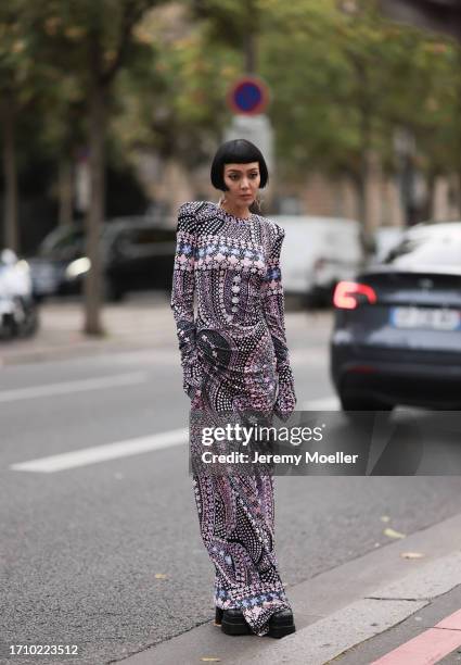 Kiwi Lee is seen outside Leonard Paris show wearing silver earrings, black and pink patterned narrow dress, black plateau boots during the Womenswear...