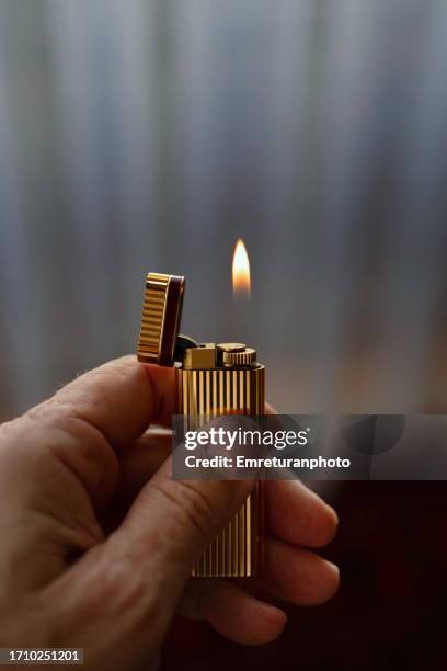close up of a  left hand holding a lighter - premium lighter stock pictures, royalty-free photos & images