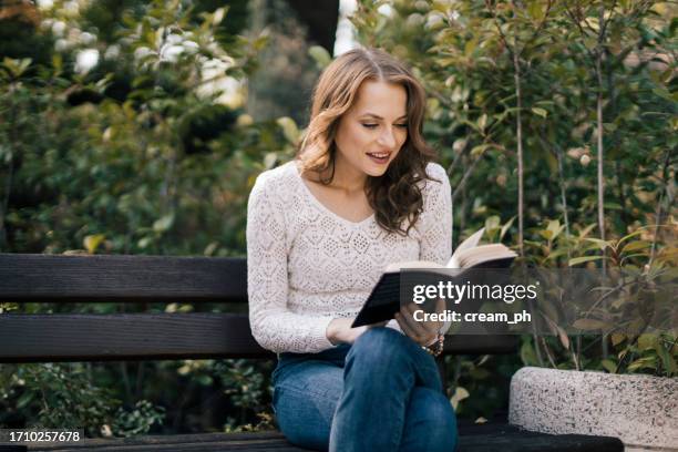 happy young woman reading an interesting book in the park - blank brochure cover stockfoto's en -beelden