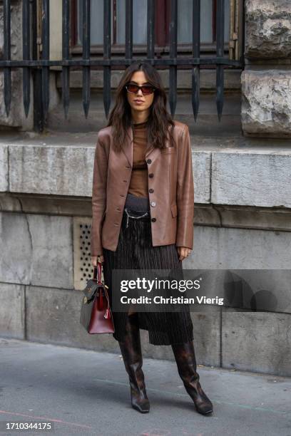 Guest wears brown jacket, pleated skirt, bag outside Hermes during the Womenswear Spring/Summer 2024 as part of Paris Fashion Week on September 30,...