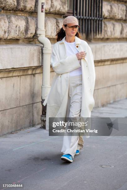 Deborah Reyner Sebag wears brown cap, creme white coat, pants, white shirt outside Hermes during the Womenswear Spring/Summer 2024 as part of Paris...