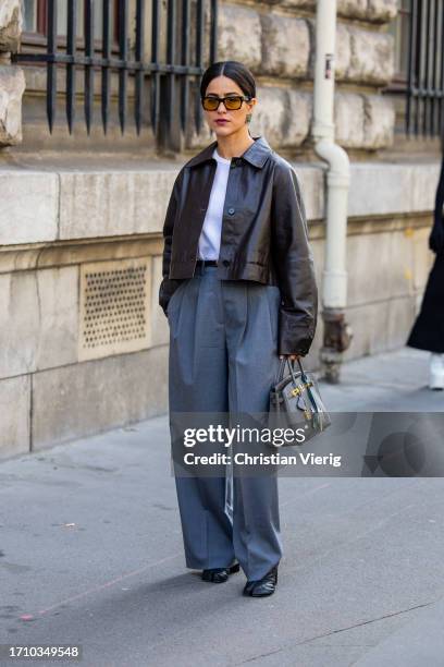 Guest wears grey pants, brown jacket, grey bag outside Hermes during the Womenswear Spring/Summer 2024 as part of Paris Fashion Week on September 30,...