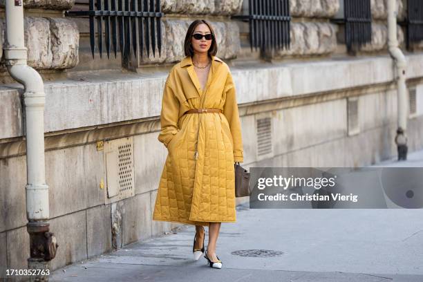 Aimee Song wears mustard yellow belted puffer coat, bag, black white pointed heels outside Hermes during the Womenswear Spring/Summer 2024 as part of...