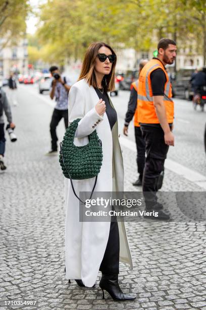 Guest wears green bag, white coat outside Carven during the Womenswear Spring/Summer 2024 as part of Paris Fashion Week on September 30, 2023 in...