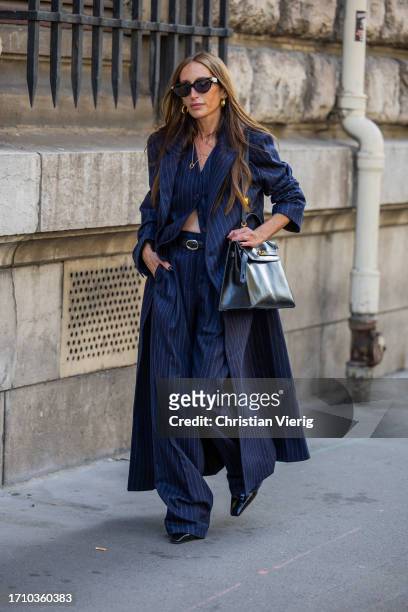 Chloe Harrouche wears navy striped coat, pants, black bag outside Hermes during the Womenswear Spring/Summer 2024 as part of Paris Fashion Week on...