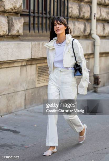 Leia Sfez wears white cropped jacket, pants, black jacket, transparent shoes outside Hermes during the Womenswear Spring/Summer 2024 as part of Paris...