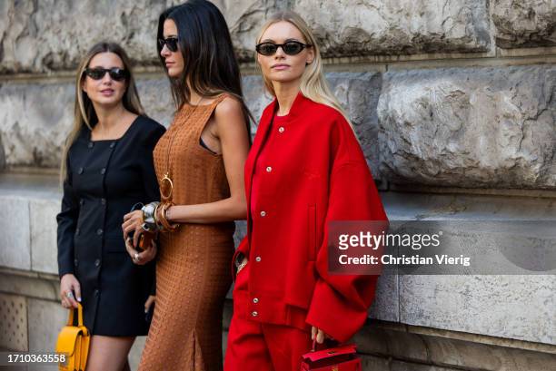 Paula Nata wears brown dress & Claire Rose Cliteur wears red oversized college jacket, bag, pants wears outside Hermes during the Womenswear...