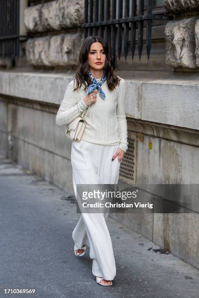 Alexandra Pereira wears white wide leg pants, creme white knit, bag, scarf outside Hermes during the Womenswear Spring/Summer 2024 as part of Paris...