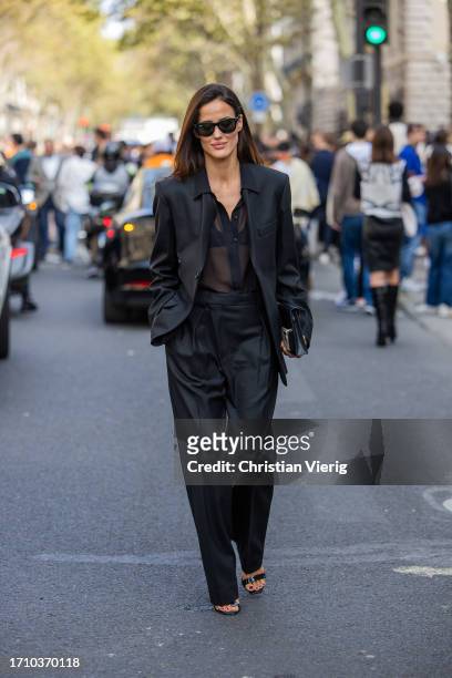Alex Riviere wears black blazer, pants, transparent blouse, bag, heels outside Hermes during the Womenswear Spring/Summer 2024 as part of Paris...