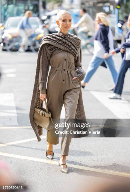 Leonie Hanne wears knitted brown scarf, overall, beige bag outside Hermes during the Womenswear Spring/Summer 2024 as part of Paris Fashion Week on...