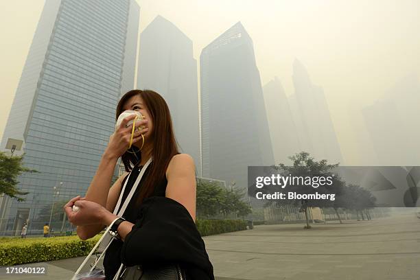 Woman covers her mouth and nose with a face mask as she walks past the central business district of Singapore, on Friday, June 21, 2013. Singapore's...