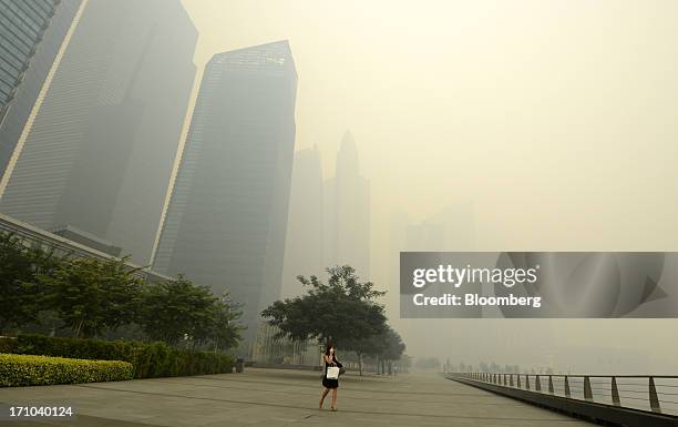 Woman covers her mouth and nose with a face mask as she walks past the central business district of Singapore, on Friday, June 21, 2013. Singapore's...