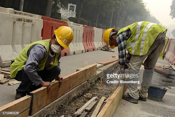 Construction workers labor by the side of a road in Singapore, on Friday, June 21, 2013. Singapore's smog hit its worst level, blanketing the...