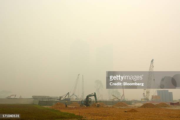 Machinery stand on a construction site at Marina Bay as buildings in the central business district, rear, stand shrouded in smog in Singapore, on...
