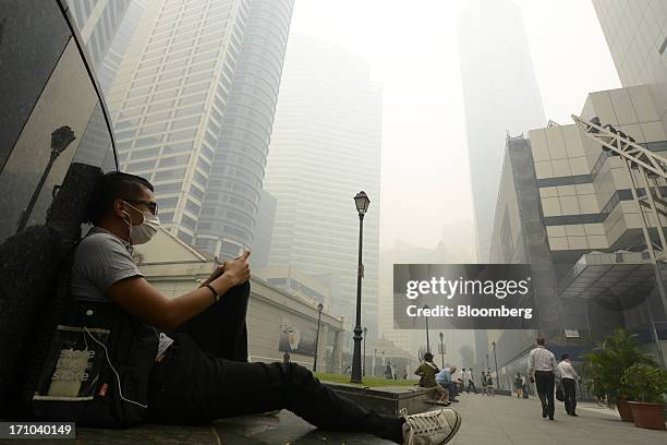 Man sits with his headphones at Raffles Place in Singapore, on Friday, June 21, 2013. Singapore's smog hit its worst level, blanketing the city-state...