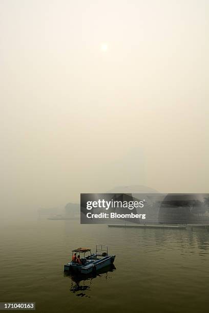 Waterfront river cleaners sit in their boat near the Marina Bay Sands hotel towers and the Sands Expo and Convention Center, center, as they stand...