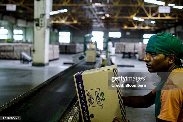 Ruchi Soya Industries Ltd. Employee waits to seal a box of one litre packs of Sunrich refined sunflower oil at the company's edible oil refinery...