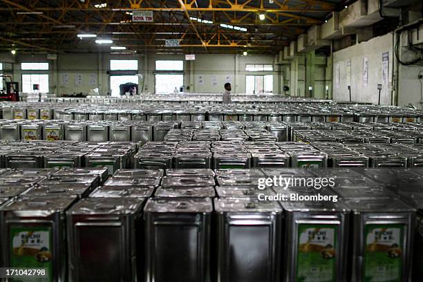 Ruchi Soya Industries Ltd. Employee walks between stacks of 15 liter tins of oil at the Ruchi Soya Industries Ltd. Edible oil refinery plant in...