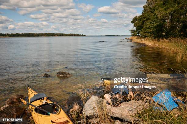 man at lake relaxing near kayaks during sunny day - kayaking stockholm stock pictures, royalty-free photos & images