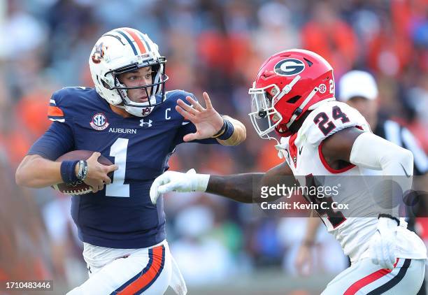 Payton Thorne of the Auburn Tigers rushes away from Malaki Starks of the Georgia Bulldogs during the third quarter at Jordan-Hare Stadium on...