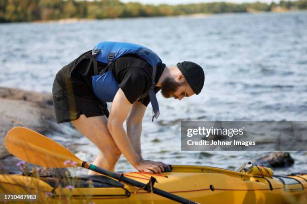 man at sea standing near kayak - stockholm summer stock-fotos und bilder