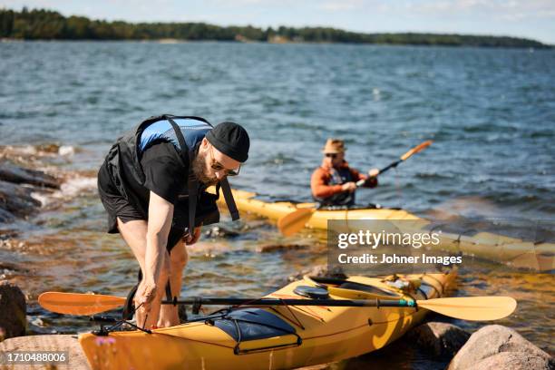 man at sea standing near kayak - stockholm summer stock-fotos und bilder