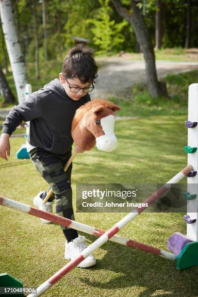 boy participating in hobby horse competition - hindernisrace paardenrennen stockfoto's en -beelden