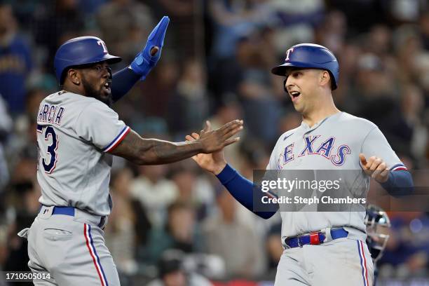 Adolis Garcia and Nathaniel Lowe of the Texas Rangers score runs against the Seattle Mariners during the third inning at T-Mobile Park on September...
