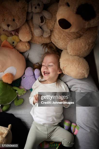 disabled girl lying on bed surrouded with teddy bears - bébé doudou photos et images de collection