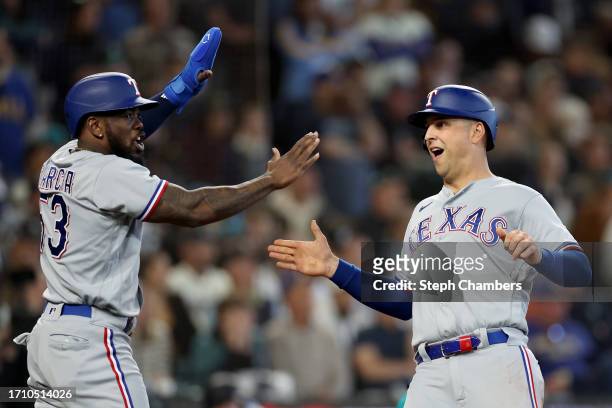 Adolis Garcia and Nathaniel Lowe of the Texas Rangers score runs against the Seattle Mariners during the third inning at T-Mobile Park on September...