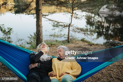 Two senior women resting in hammock at lakeshore Two senior women resting in hammock at lakeshore