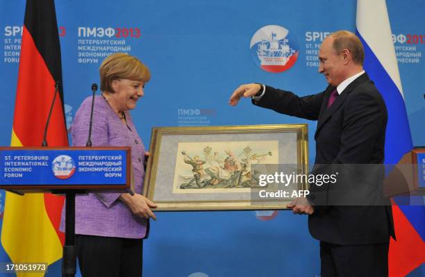 Russia's President Vladimir Putin presents Germany's Chancellor Angela Merkel an old lithograph dedicated to the signing of a Russian-German trade...