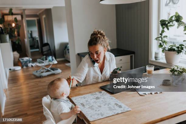 multitasking mother taking care of baby and working from home - polyvalence photos et images de collection