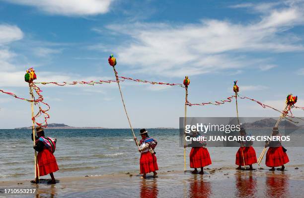 Aymara peasants dressed in typical ceremonial attire dance making offerings on the shore of Titicaca Lake, close to the village of Perka, Puno...
