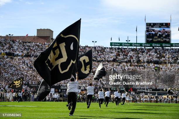 Members of the Colorado Buffaloes spirit team run across the field with flags before a game between the Colorado Buffaloes and the USC Trojans at...