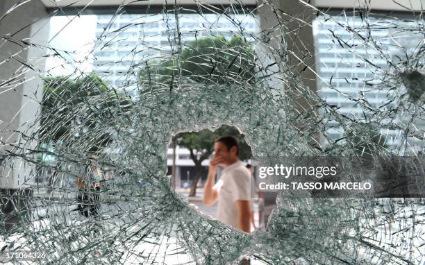 Pedestrians pass by a bank whose windows were broken during a protest overnight in downtown Rio de Janeiro, Brazil, on June 21, 2013. The 2014 World...