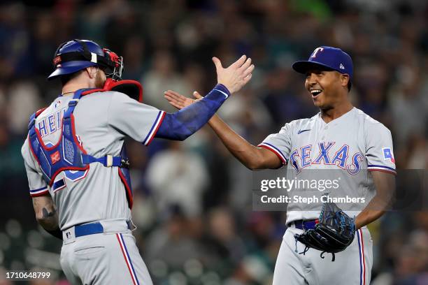 Jonah Heim and Jose Leclerc of the Texas Rangers celebrate after beating the Seattle Mariners 6-1 to clinch a 2023 MLB playoff berth at T-Mobile Park...