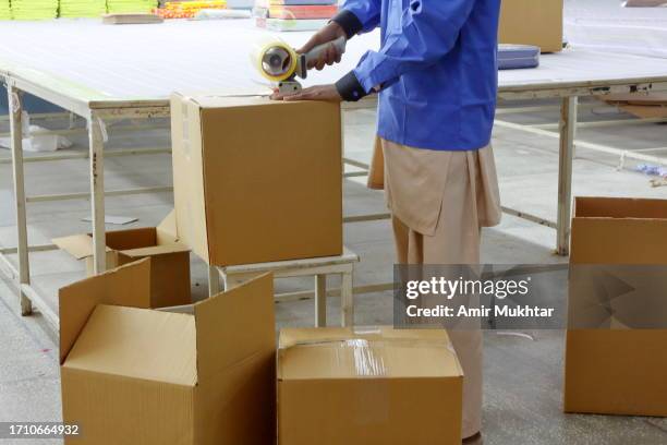 sealing cardboard boxes with adhesive tape for online order in storage room. - pakistan hospital stock pictures, royalty-free photos & images